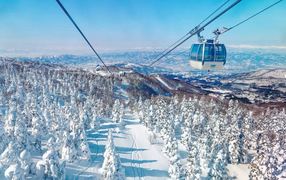 zao cable car flying over a snowy ski piste