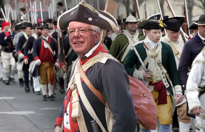bernie sanders wearing a patriot hat speaking at a rally