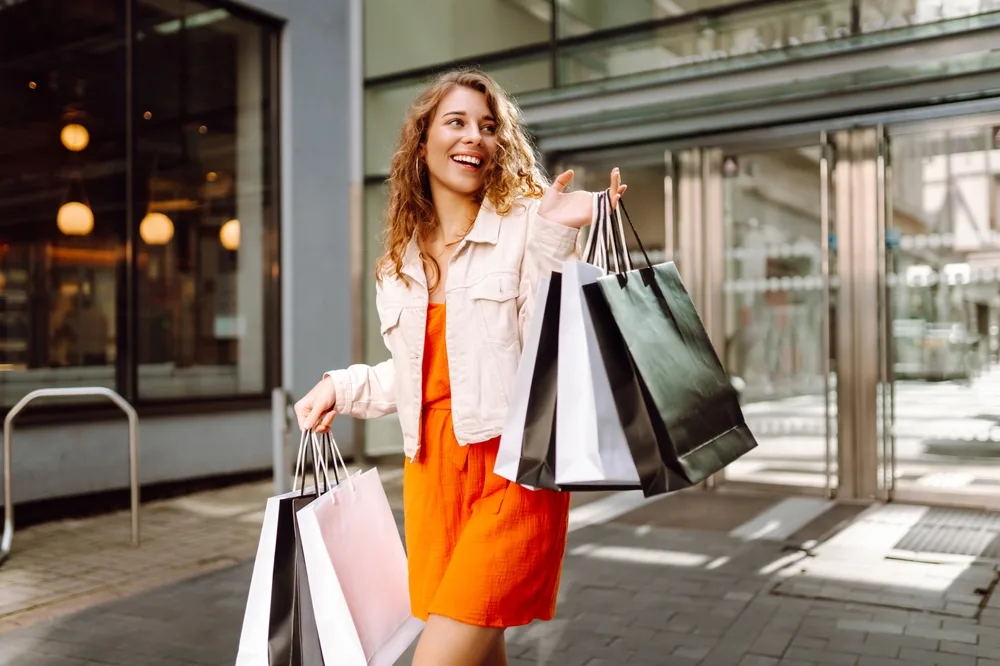 cheerful woman enjoying shopping on a sunny day carrying bags