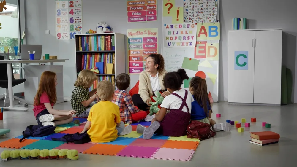 children sitting on floor listening to teacher explain lesson