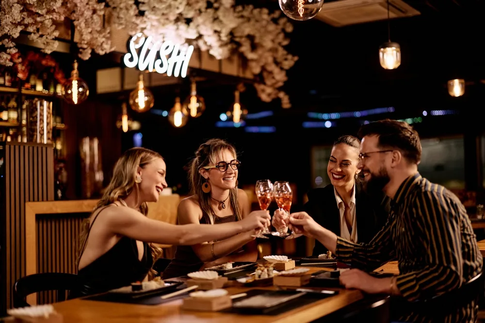 friends celebrating with toasts at a sushi restaurant