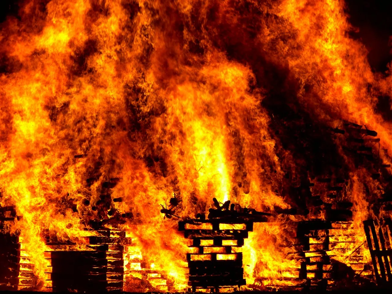 wooden pallets burning intensely with orange flames and smoke