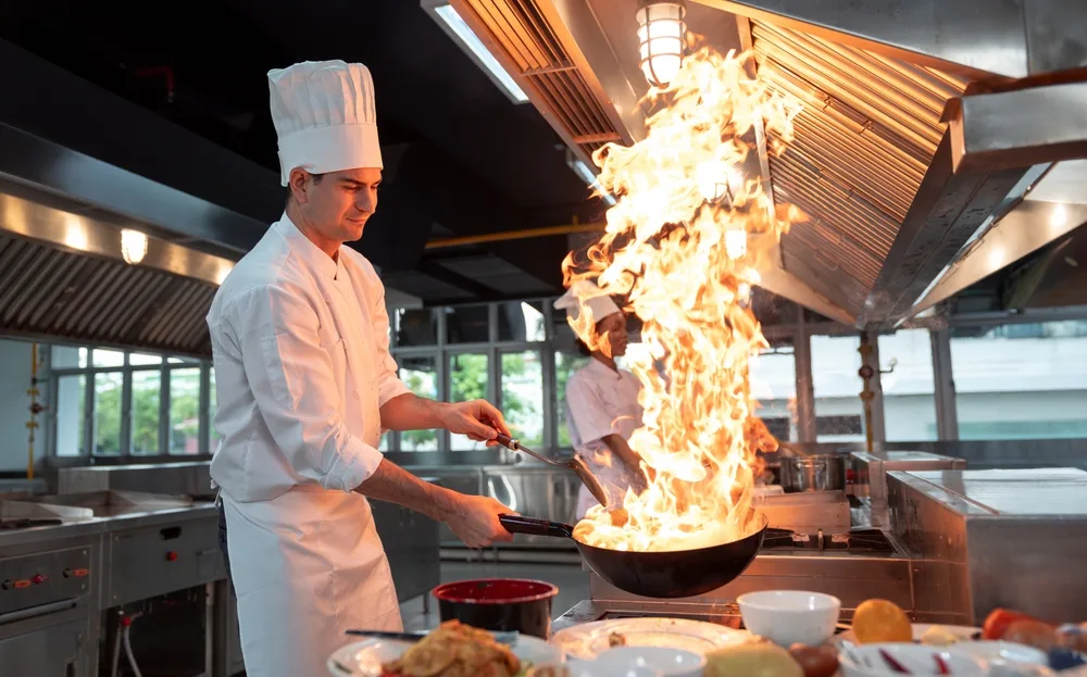 professional chef cooking with high flame on restaurant stove