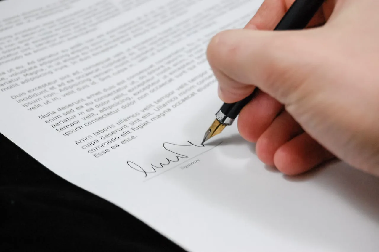 signing a contract with a pen on a table