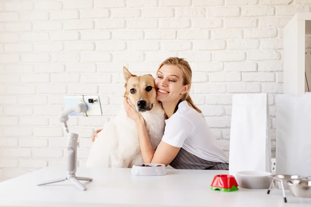 smiling young woman blogger influencer at home with her mixed dog