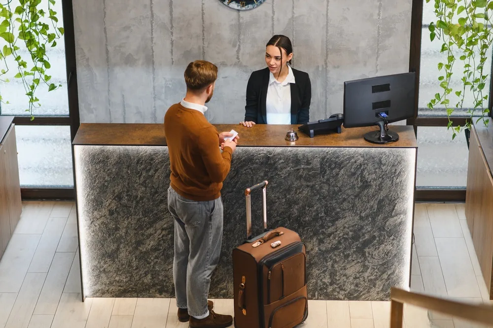 traveler checking into a contemporary hotel lobby interacting with staff