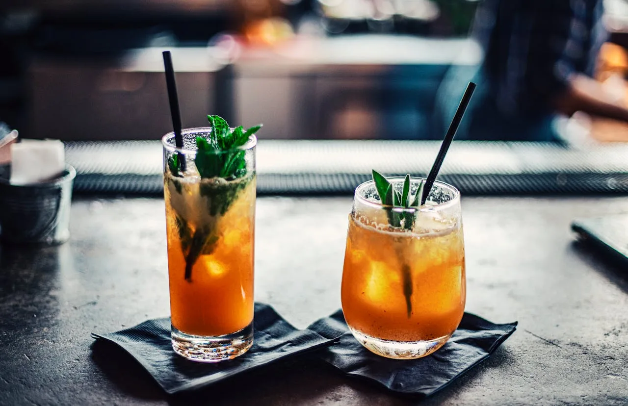 two colorful cocktails on a bar top