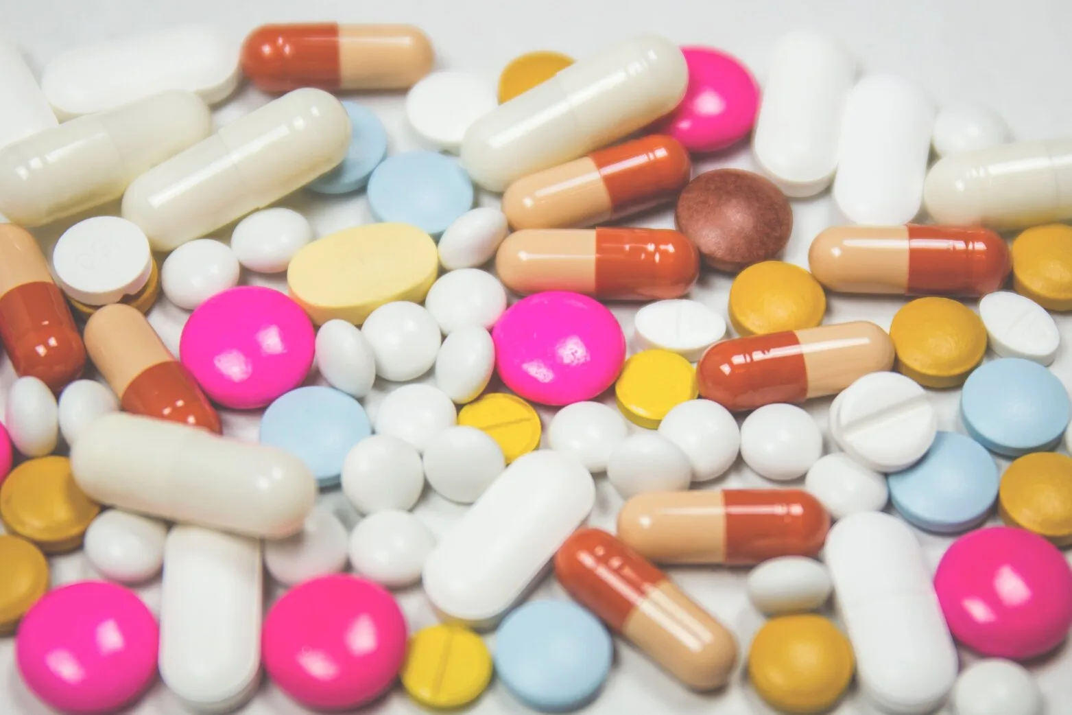 a variety of colorful pills scattered on a white surface