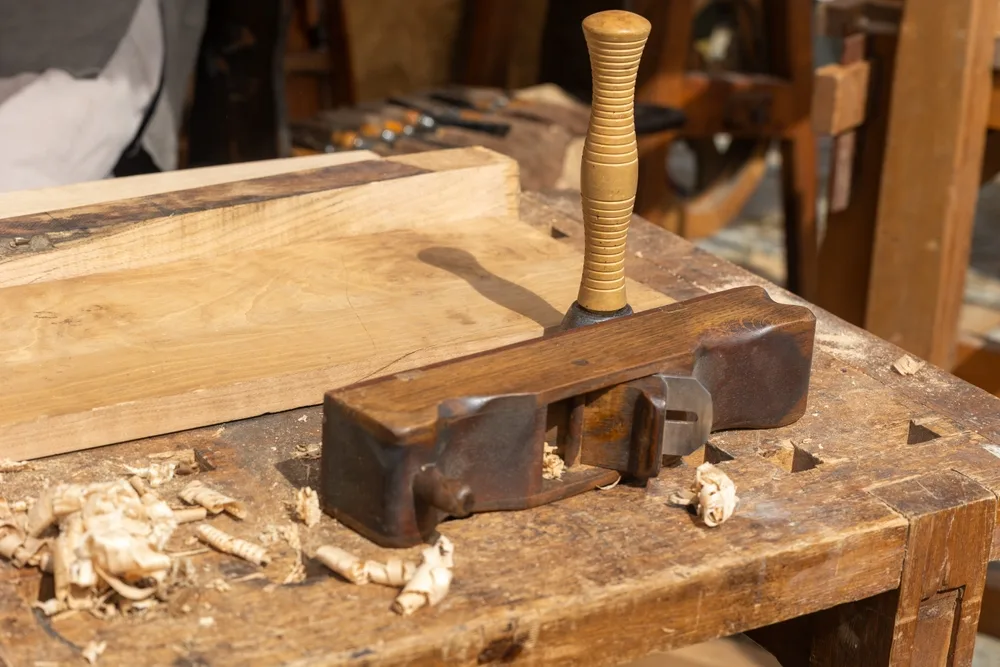 carpenter using a traditional wood plane for woodworking