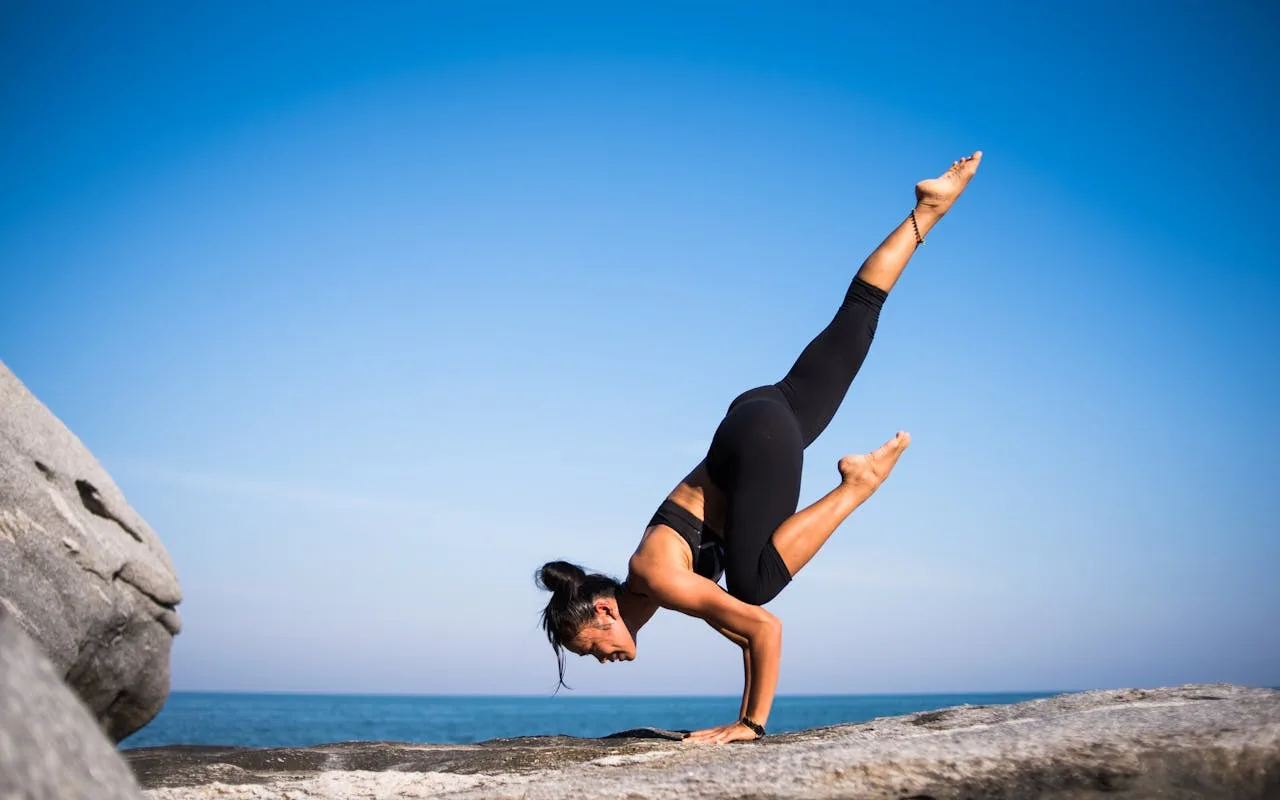 woman practicing yoga by the ocean at sunrise
