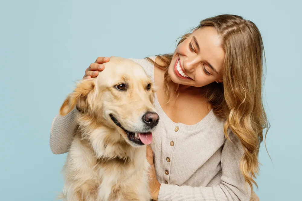 young happy woman smiling with her golden retriever best friend
